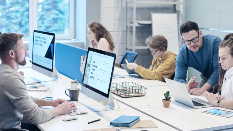mesa-em-escritorio-com-cinco-pessoas-trabalhando-em-computadores