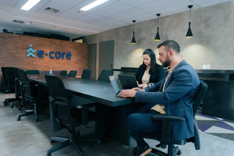 dos personas trabajando en una mesa en la oficina de e-Core
